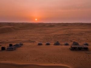 Eine Gruppe Kamele in der Wüste bei Sonnenuntergang in der Unterkunft Sands Dream Tourism Camp in Shāhiq