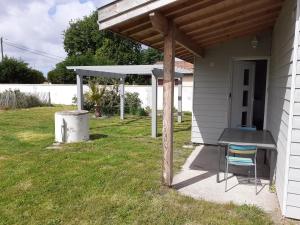 un patio con una mesa y una pérgola en Maison, en Hourtin