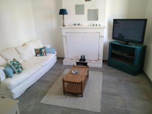 ein Wohnzimmer mit einem weißen Sofa und einem TV in der Unterkunft Maison in Hourtin