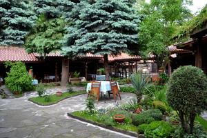 un patio con mesa y sillas en un jardín en Krasteva House en Berkovitsa