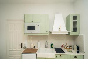 a white kitchen with green cabinets and a sink at La Maison de Lilac-Luxurious Olive Grove apartments in Platis Gialos