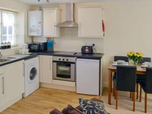 a kitchen with white cabinets and a table and a stove at Coots Nest in Stalham