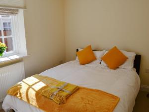 a bedroom with a bed with an orange towel on it at Coots Nest in Stalham