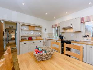 una cocina con armarios blancos y una mesa con una cesta. en Castlemans Stables West en Sedlescombe