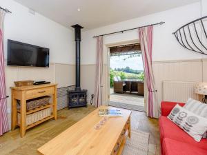 a living room with a red couch and a wood stove at Castlemans Stables West in Sedlescombe