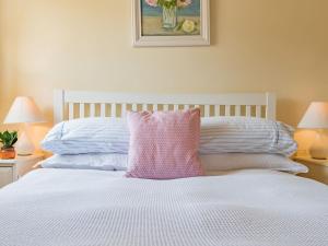 a white bed with a pink pillow on top of it at Shepherds Cottage in Pett