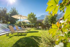 a row of chairs and an umbrella in a yard at Hotel Villa Stefania in San Candido