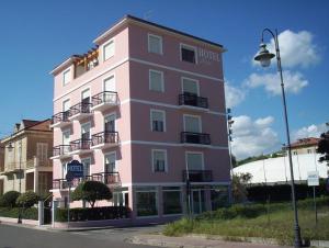 un edificio rosa con balcones y luz de la calle en Hotel Rosa Meublé, en Porto San Giorgio