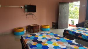 - une chambre avec un lit, une télévision et une porte dans l'établissement Gogona Homestay, à Guwahati