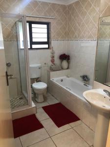 ein Badezimmer mit einer Badewanne, einem WC und einem Waschbecken in der Unterkunft Sanlou in Port Shepstone