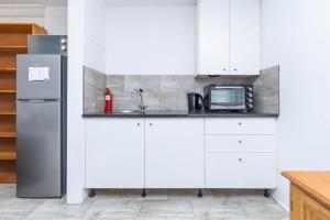 a white kitchen with a sink and a refrigerator at Surburban Bliss - Claremont in Cape Town