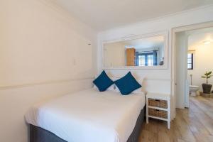 1 dormitorio con cama blanca y almohadas azules en Surburban Bliss - Claremont, en Ciudad del Cabo