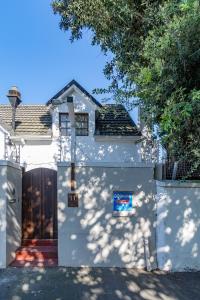 a white house with a door and a fence at Surburban Bliss - Claremont in Cape Town