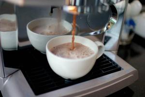 two cups of coffee being brewed in a microwave at Double J Hotel in Chiang Mai