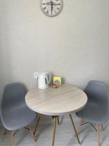 einen Tisch mit zwei Stühlen und eine Uhr an der Wand in der Unterkunft VIP квартира центр in Oral