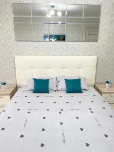 ein Schlafzimmer mit einem großen weißen Bett mit blauen Kissen in der Unterkunft VIP квартира центр in Oral