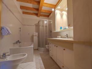 ein Badezimmer mit zwei Waschbecken, einer Badewanne und einer Dusche in der Unterkunft Appartement Haidacher in Innichen