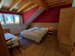 Appartement Haidacher في سان كانديدو: غرفة نوم بسريرين وجدار احمر