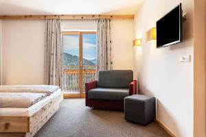 um quarto com uma cama, uma cadeira e uma janela em Hohenegg Apartment Julian em Sarentino