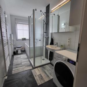a bathroom with a shower and a sink and a washing machine at Ferienwohnung NR1 in Großräschen
