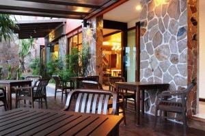 a restaurant with tables and chairs and a stone wall at The Charm Boutique Resort in Khon Kaen