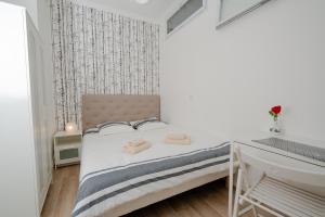 a small white bedroom with a bed and a desk at Appartement de charme avec vue sur place de la République in Paris