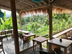 porche con mesas y sillas y vistas al bosque en The Green ujung Villa en Ujung