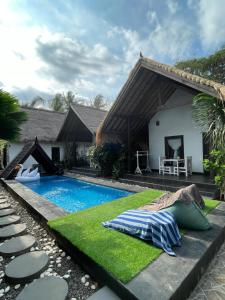 un cortile con piscina e una casa di Black & White Cottages a Gili Trawangan