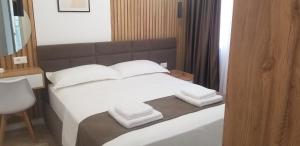 Un dormitorio con una cama con almohadas blancas y un espejo. en White Apartment, en Tirana