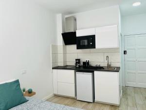 uma pequena cozinha com armários brancos e um lavatório em Coqueto apartamento a 50 metros de la playa em Las Palmas de Gran Canaria