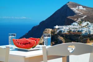 a table with a slice of watermelon on top of a table with a view at Belvedere Apartments in Chora Folegandros