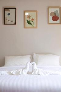 łóżko z białą pościelą i dwoma obrazkami na ścianie w obiekcie Yamee Homestay Cafe w mieście Ban Pha Mi