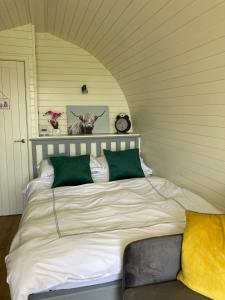 a bedroom with a large bed with green pillows at Abbey farm luxury glamping in Rhuddlan