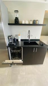 a black kitchen counter with a sink and a dishwasher at Very romantic seaview appartment with warm pool in Patalavaca