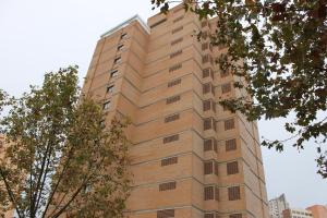 un edificio alto de ladrillo con árboles delante de él en Apartamentos Alpha, en Benidorm