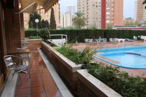 un patio con piscina, mesa y sillas en Apartamentos Alpha, en Benidorm