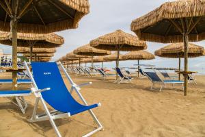 een groep stoelen en parasols op een strand bij Hotel Mara in Ortona