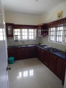a large kitchen with wooden cabinets and windows at Royal Homes in Kakkanad