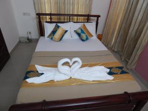 Una cama con dos toallas de cisne. en Royal Homes, en Kakkanad