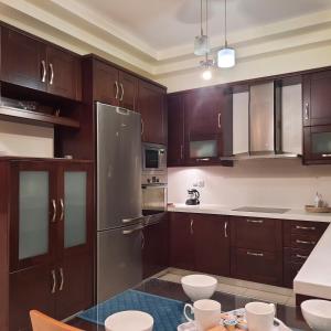 una cucina con armadi in legno e frigorifero in acciaio inossidabile di Family Comfortable Spacious Apartment a Heraklion