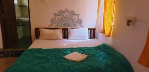 a bedroom with a bed with a green blanket at TantraLoka Retreat Centre in Arambol