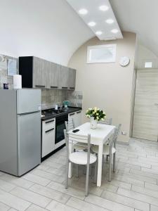 Antonio’s house في نابولي: مطبخ مع طاولة بيضاء مع كراسي وثلاجة
