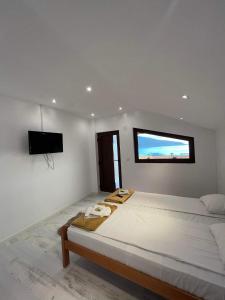 a white bedroom with a large bed and a flat screen tv at Vila Legrand in Baziaş