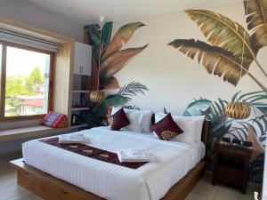 a bedroom with a large white bed with plants on the wall at Wayla Villa@Maikhaobeach in Mai Khao Beach