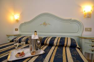 uma cama com uma bandeja de comida e uma garrafa de vinho em Hotel Orion em Veneza