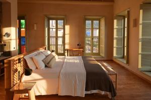 a bedroom with a large white bed with windows at Casa Mediterraneo Hotel in Meyisti