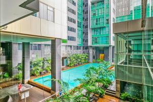 ein Apartmentgebäude mit einem Pool und Palmen in der Unterkunft LILY by Kozystay - Kuningan in Jakarta