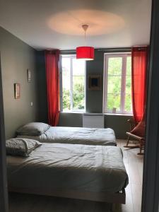 two beds in a bedroom with red curtains at Niarnia in Abbeville