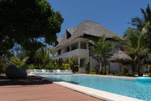 a villa with a swimming pool in front of a house at Kuwa Zanzibar in Kiwengwa