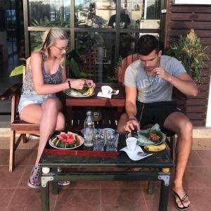 Ein Mann und eine Frau sitzen an einem Tisch mit Essen in der Unterkunft The nearest Surattani airport in Surat Thani